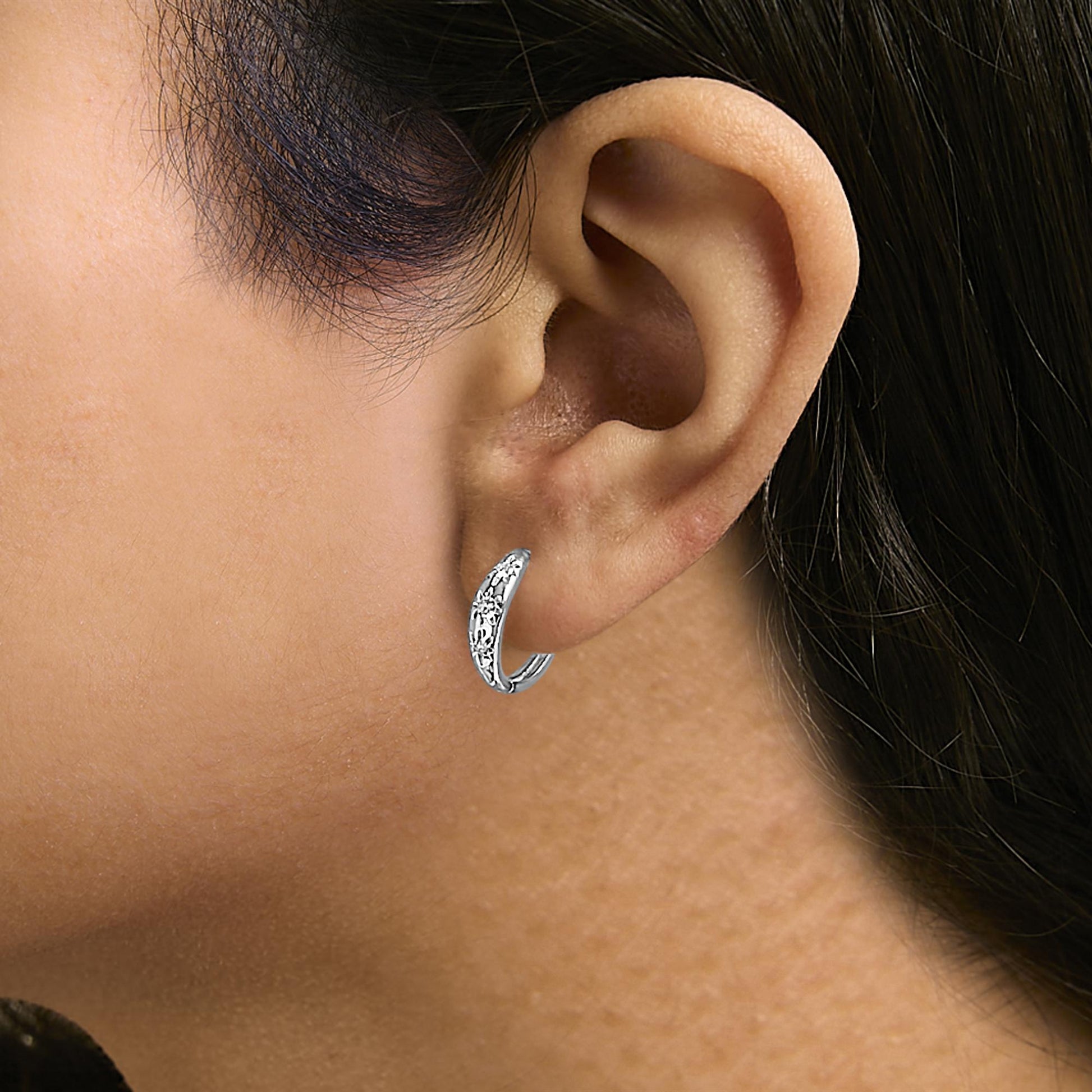 Close-up side view of a model wearing a white metal hoop earring adorned with multiple round white gemstones in prong settings.