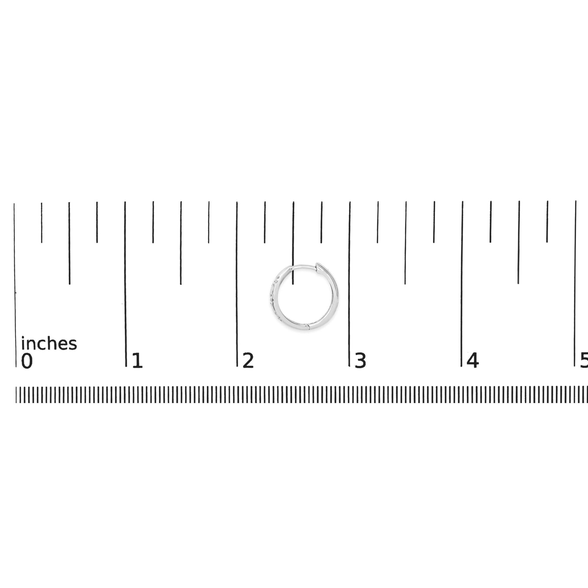 White metal hoop earring with round white gemstones in prong setting, shown on a ruler scale from a top-down angle.