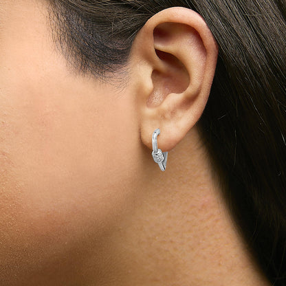 Close-up side view of a model wearing white metal hoop earrings with a cluster of small round white gemstones in a shared prong setting.