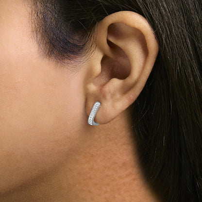 Close-up side view of a white metal earring with round white gemstones in a shared prong setting, worn on a model's ear.