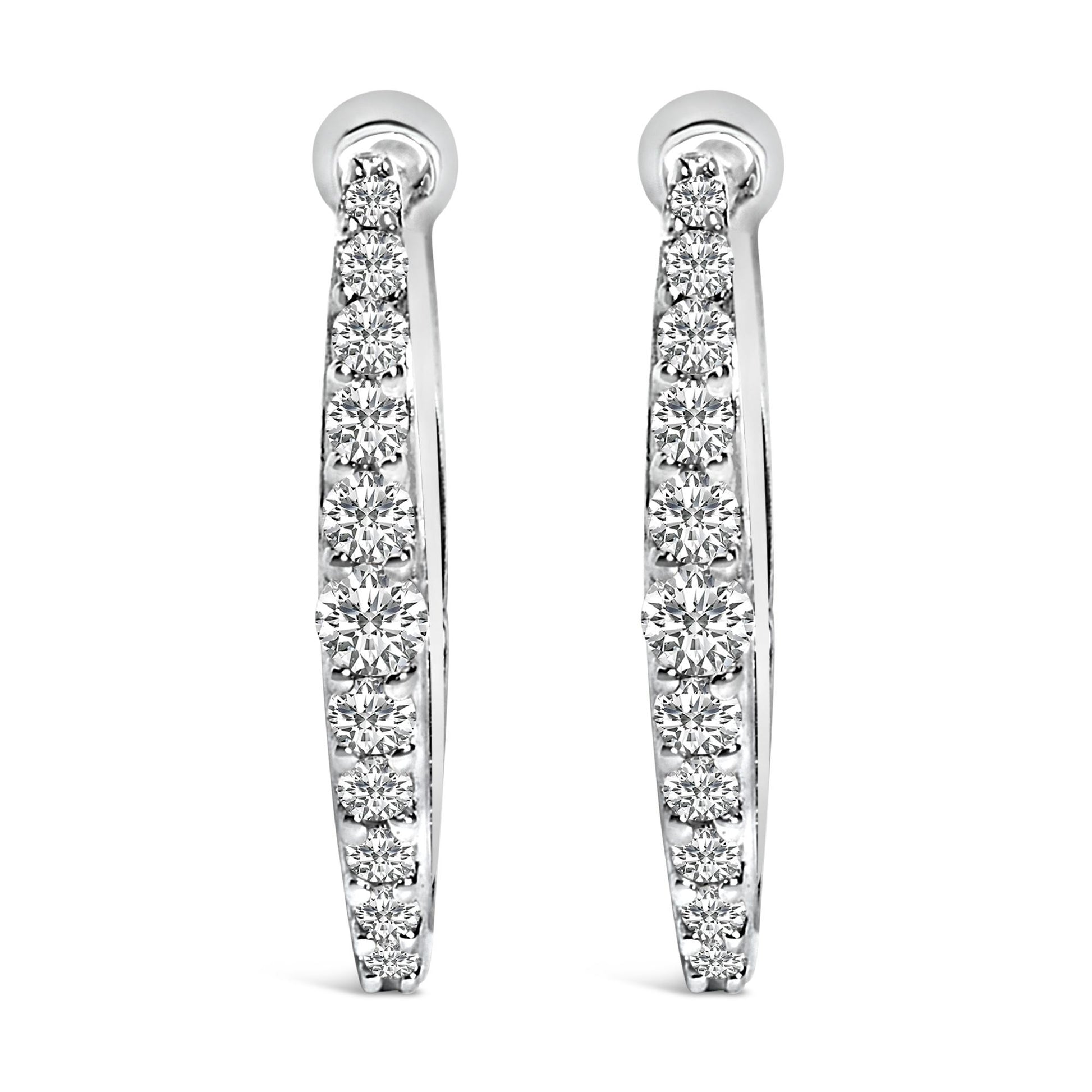 Front view of a pair of white metal hoop earrings each set with a row of round white gemstones in a shared prong setting.