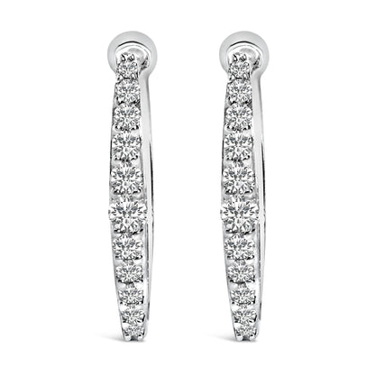 Front view of a pair of white metal hoop earrings each set with a row of round white gemstones in a shared prong setting.