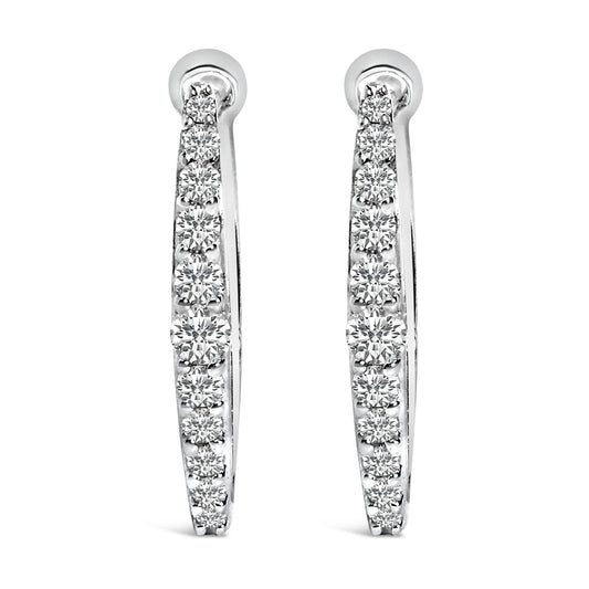 Front view of a pair of white metal hoop earrings each set with a row of round white gemstones in a shared prong setting.