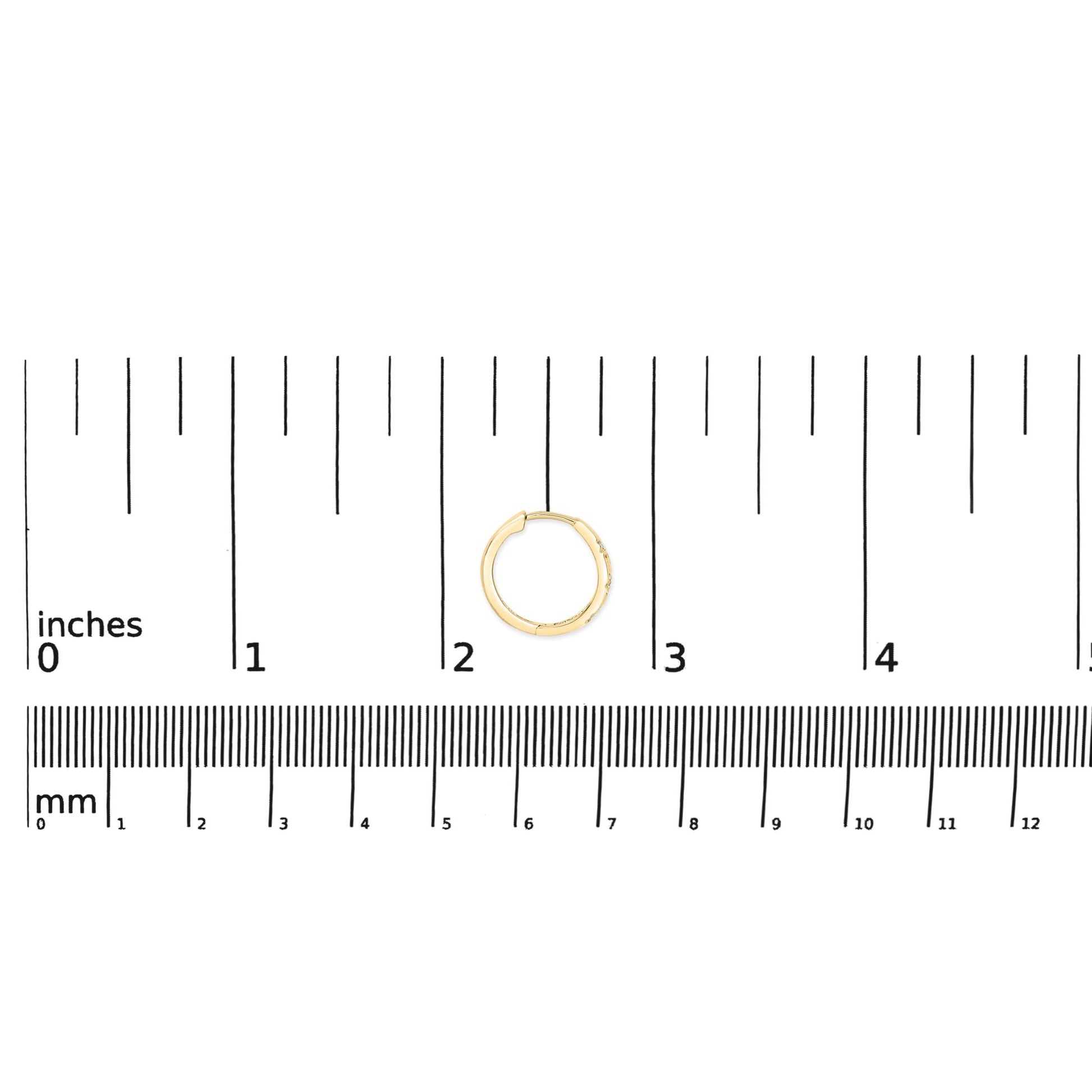 Yellow metal hoop earring with six round white gemstones in prong settings, shown on a scale from above.