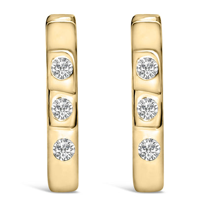 Front-facing close-up of a pair of yellow metal earrings each set with three round white gemstones in bezel settings.