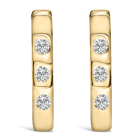 Front-facing close-up of a pair of yellow metal earrings each set with three round white gemstones in bezel settings.