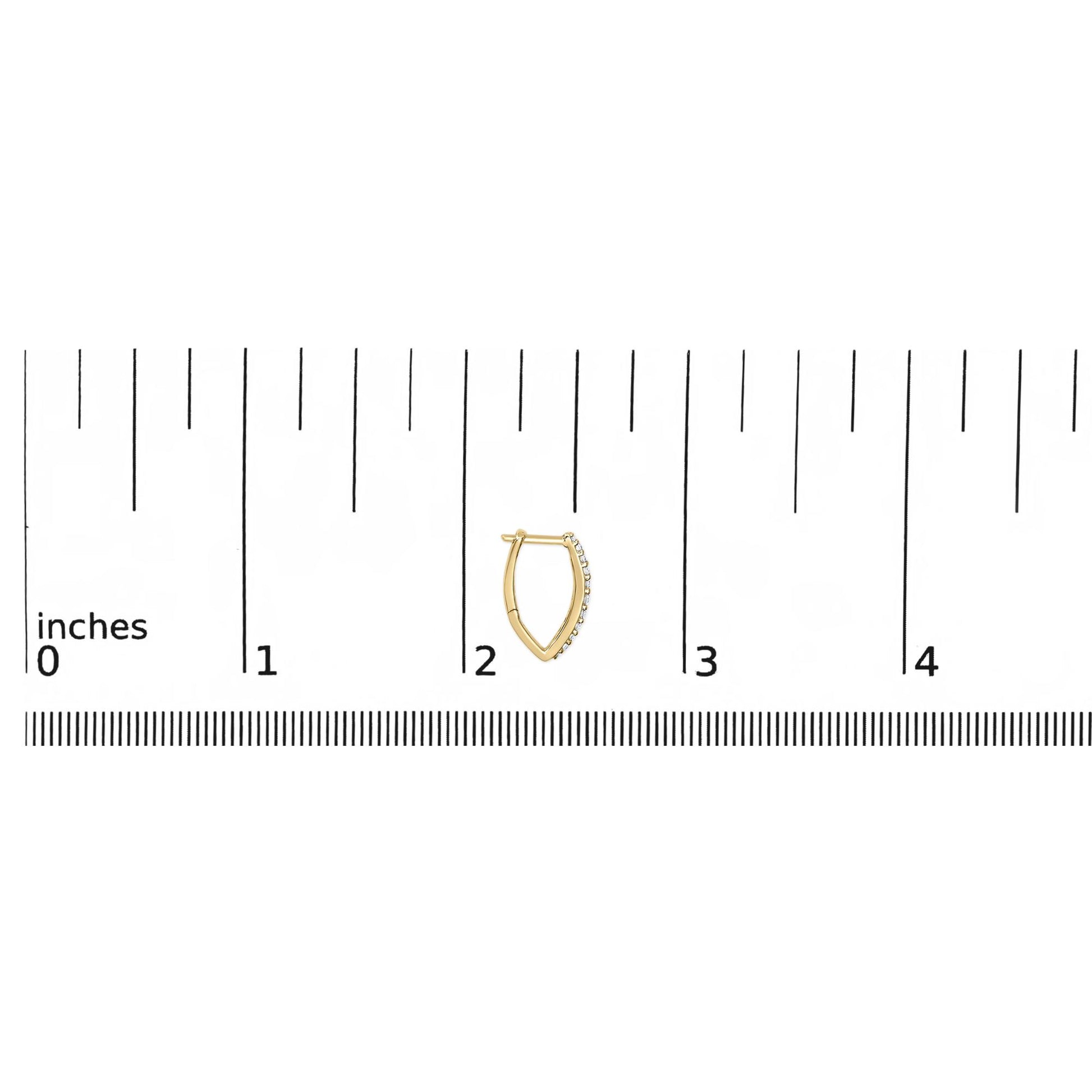 Yellow metal earrings with a V-shaped design, featuring a row of round white gemstones set in shared prongs along one side, shown on a ruler scale from a top-down angle.