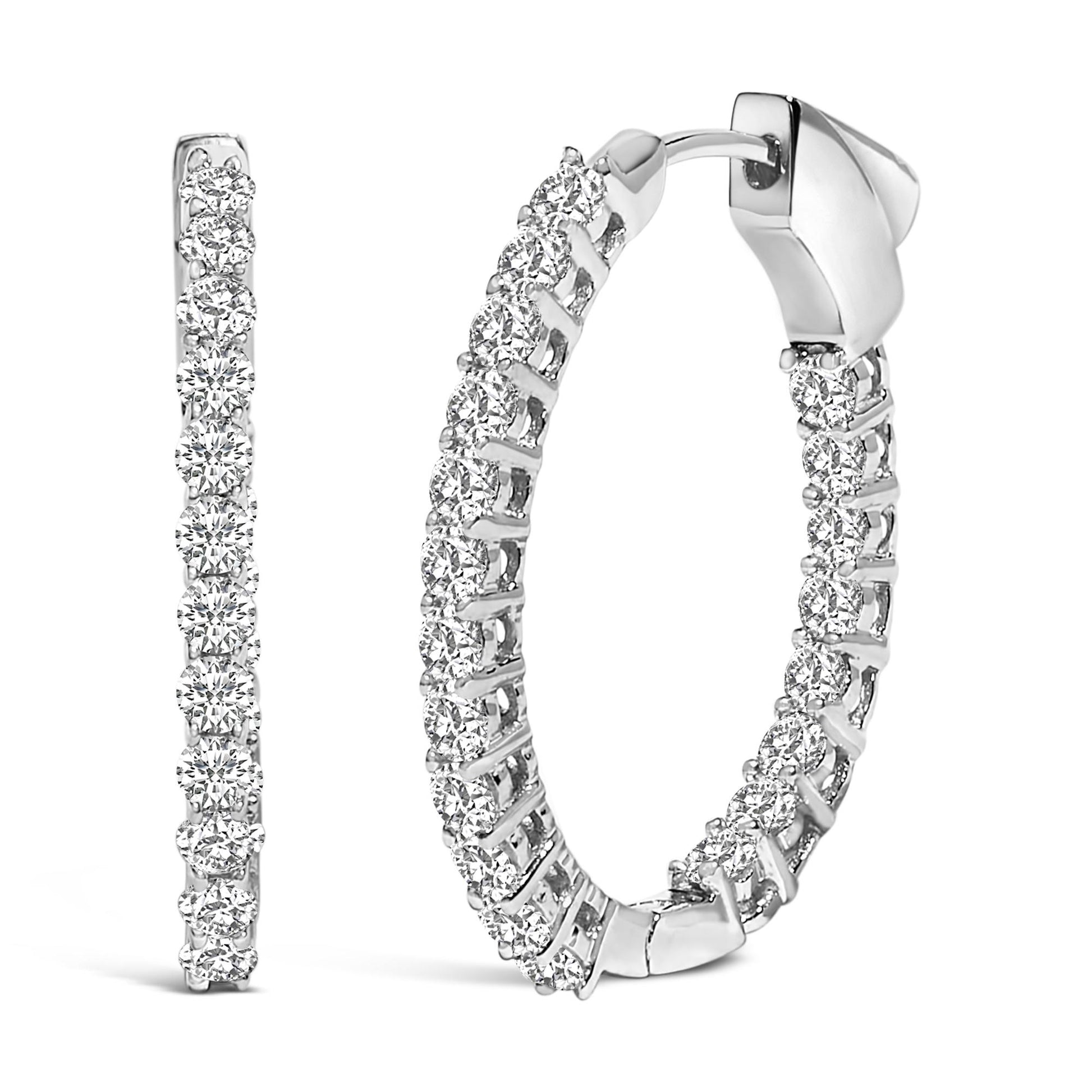 Close-up front and side angled view of a pair of white metal hoop earrings, each set with multiple round white gemstones in a shared prong setting.