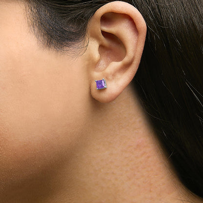Close-up side angle of a model wearing white metal stud earrings with square purple gemstones in four-prong settings.