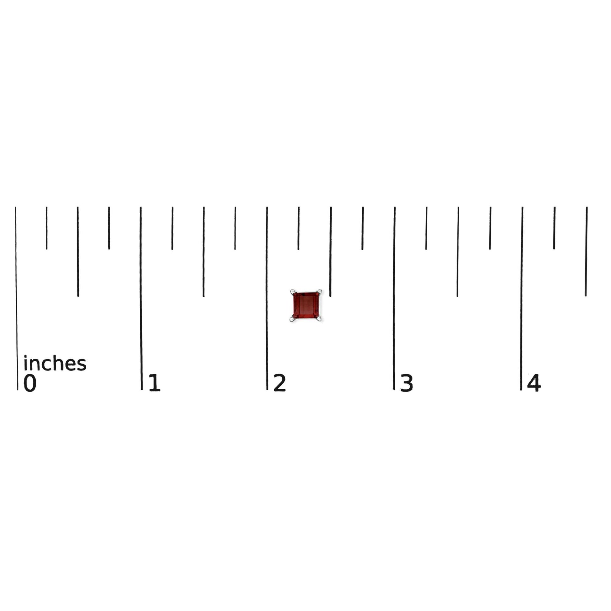 Close-up top view of a red princess-shaped gemstone earring with four-prong white metal setting shown on a ruler scale.