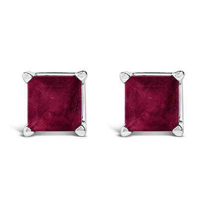 Close-up front view of a pair of white metal square stud earrings with princess-cut red gemstones in four-prong settings.