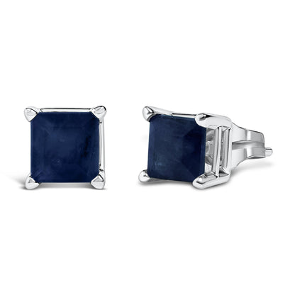 Pair of white metal stud earrings with princess-shaped blue gemstones in four-prong settings, shown at front and side angles on a white background.