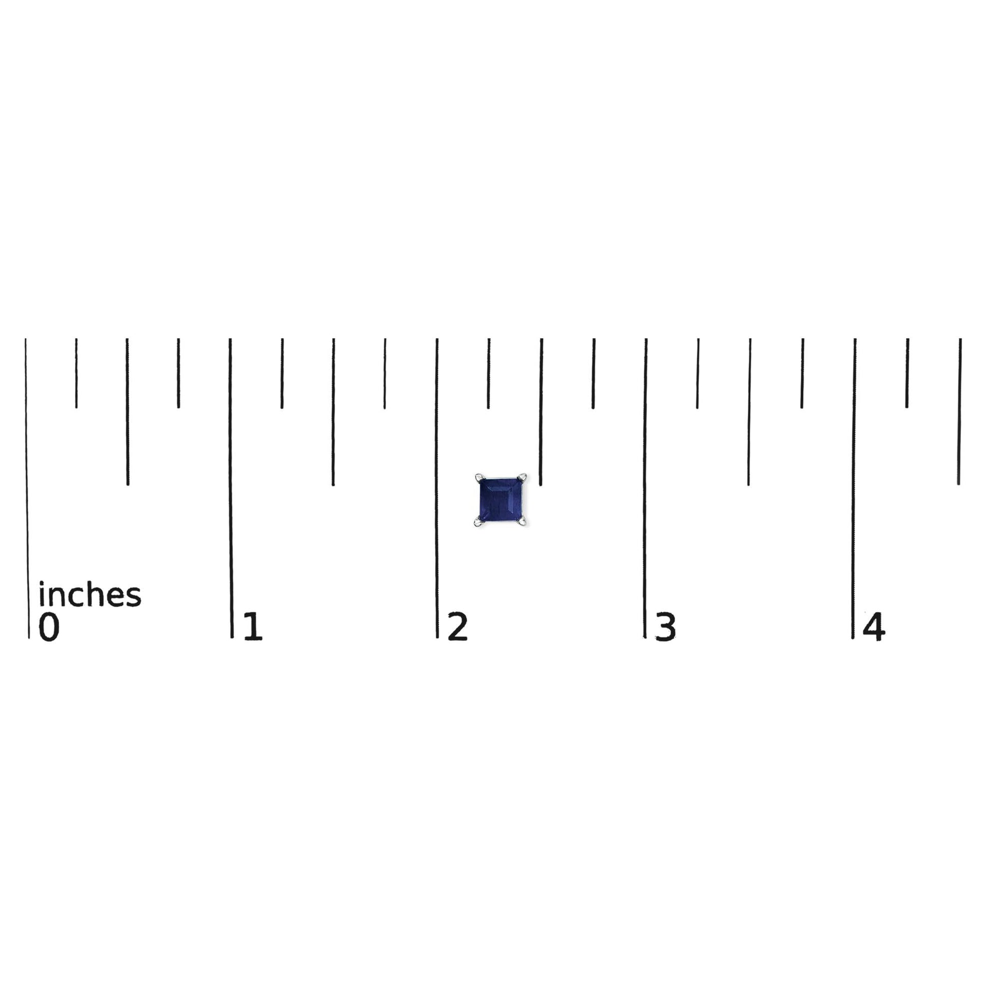 Earring with a blue princess-shaped gemstone in a four-prong white setting, shown flat on a ruler for scale from a top-down angle.