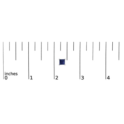 Earring with a blue princess-shaped gemstone in a four-prong white setting, shown flat on a ruler for scale from a top-down angle.