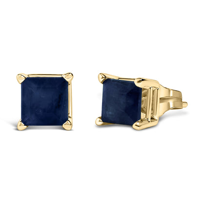 Pair of yellow metal stud earrings each featuring a princess-shaped blue gemstone in a four-prong setting, shown from front and side angles on a white background.