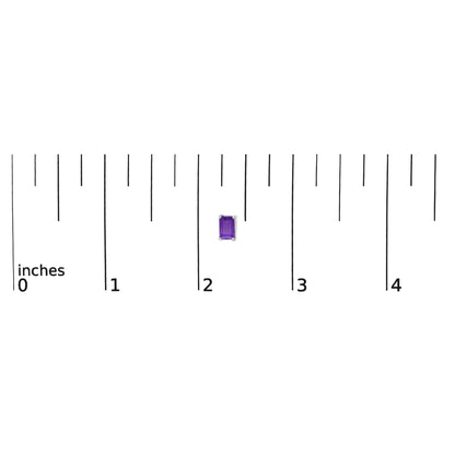 Close-up shot of a single emerald-shaped purple gemstone earring in a four-prong white setting shown on a measurement scale.