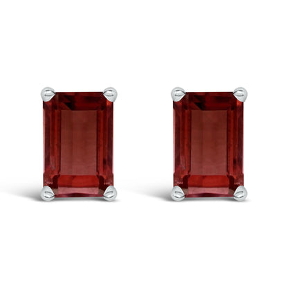 Close-up front view of a pair of white metal earrings with rectangular red gemstones set in four-prong settings.