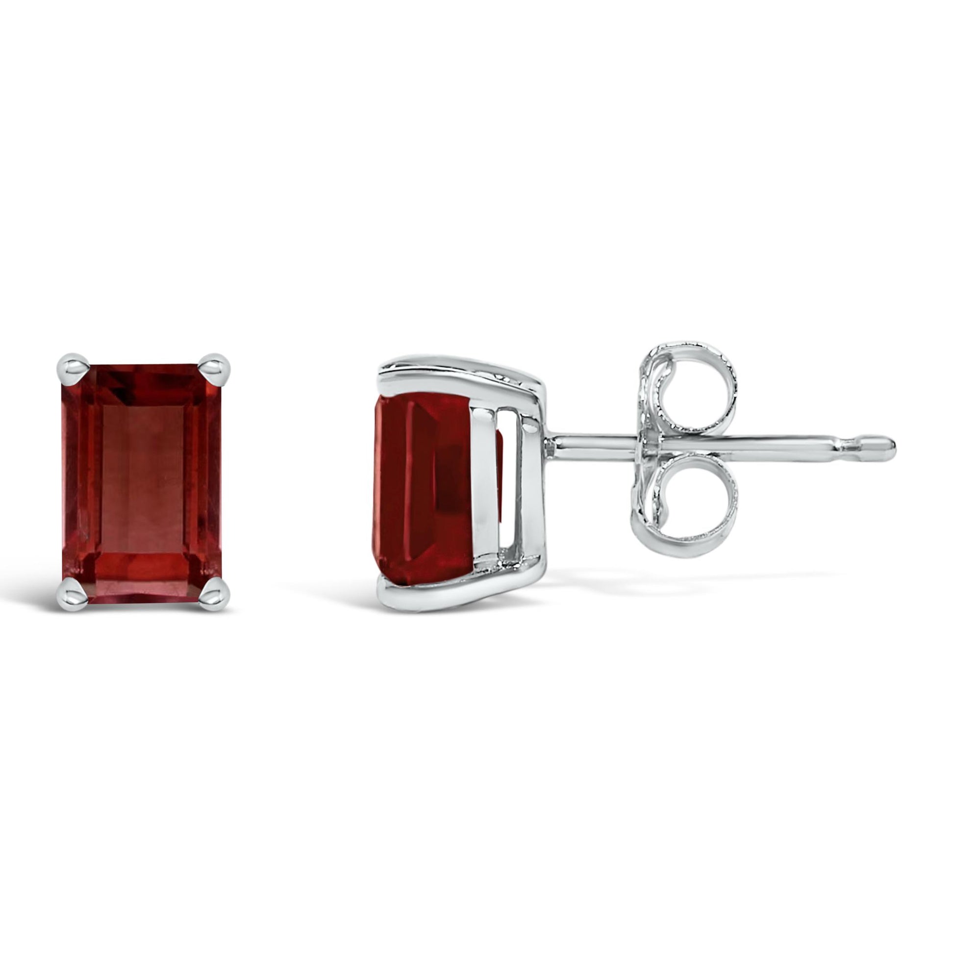 Pair of white metal stud earrings with emerald-shaped red gemstones in four-prong settings, shown from the front and side on a white background.