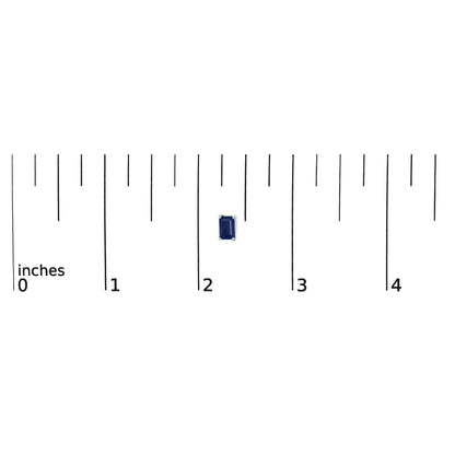 Single white metal earring with a blue emerald-shaped gemstone in a four-prong setting, shown on a ruler for scale from a top-down angle.