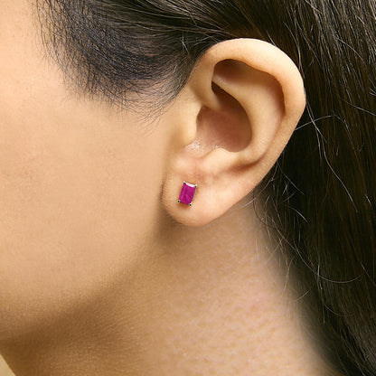 Close-up side view of a model wearing a yellow metal earring featuring a rectangular red gemstone in a four-prong setting.
