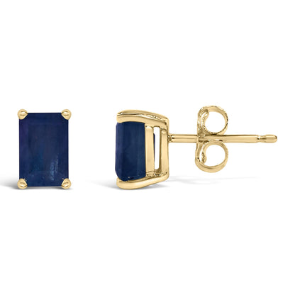 Pair of yellow metal stud earrings with emerald-shaped blue gemstones in four-prong settings, shown from front and side angles on a white background.