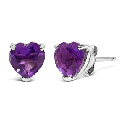 Pair of white metal stud earrings with heart-shaped purple gemstones in a 3-prong setting, shown from a front and side angle on a white background.