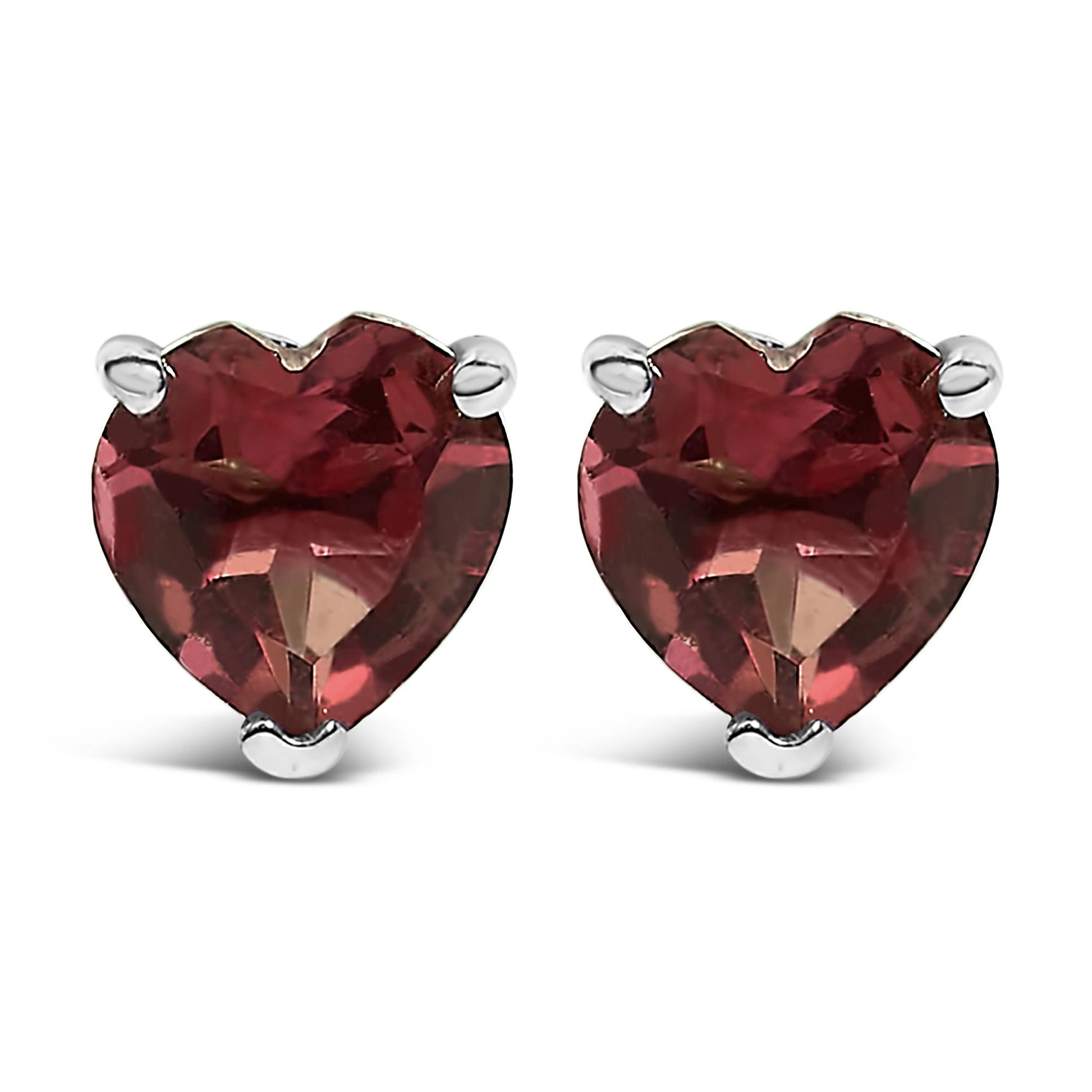 Pair of white metal stud earrings with heart-shaped red gemstones in three-prong settings, shown from the front angle.
