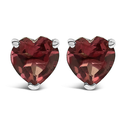 Pair of white metal stud earrings with heart-shaped red gemstones in three-prong settings, shown from the front angle.