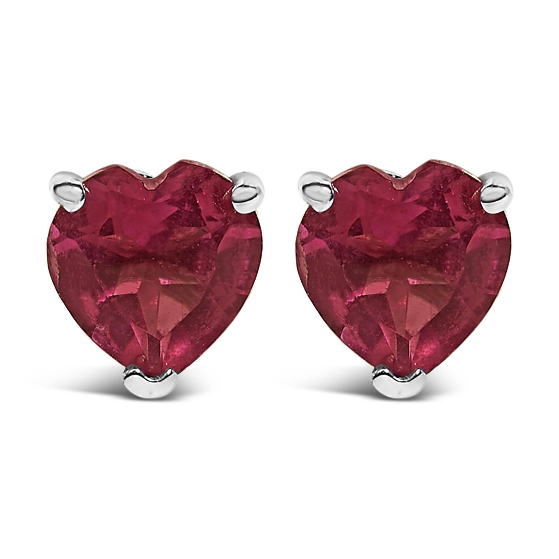 Front view of a pair of white metal stud earrings featuring heart-shaped red gemstones in 3-prong settings.
