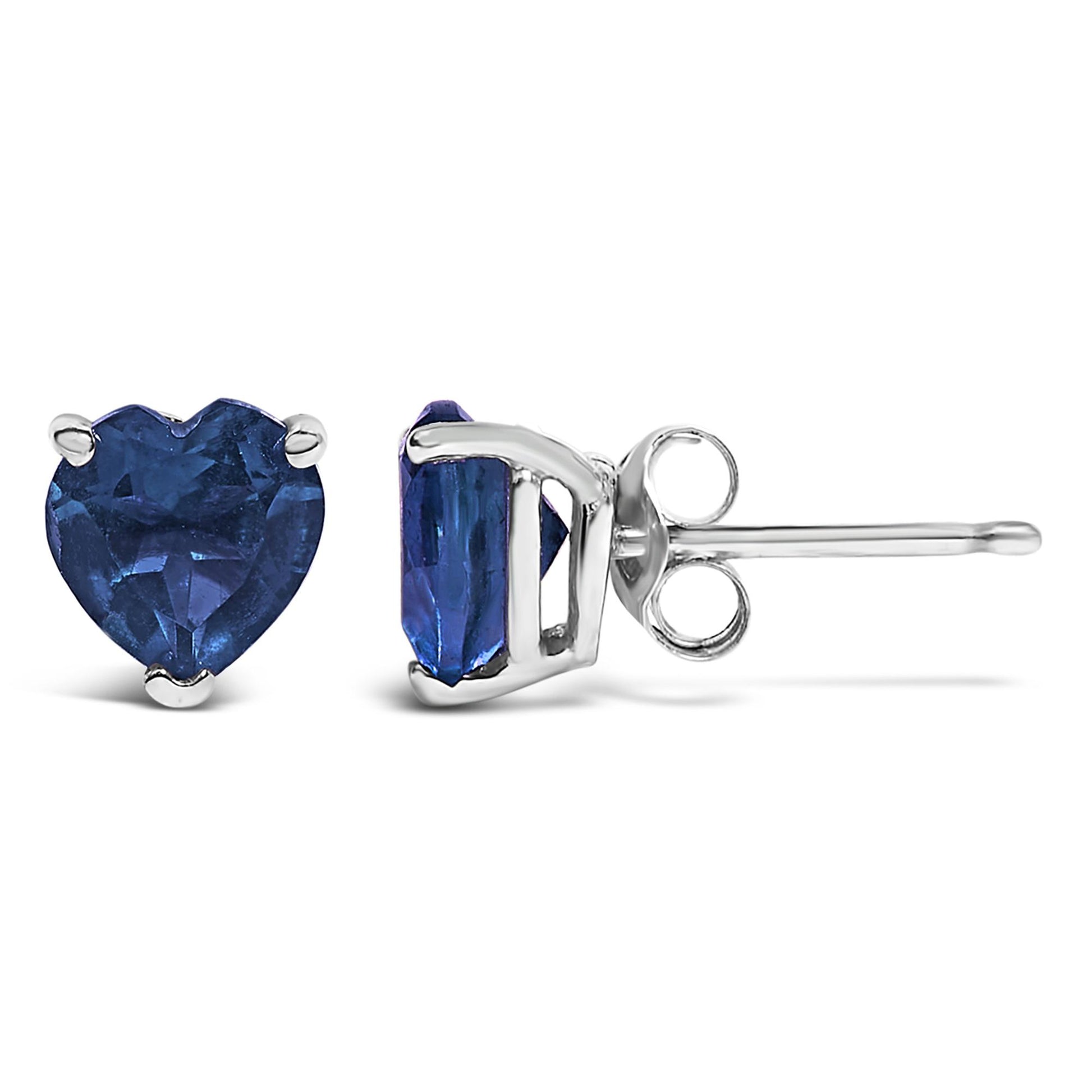 Pair of white metal stud earrings featuring heart-shaped blue gemstones set in three-prong settings, shown from front and side angles on a white background.