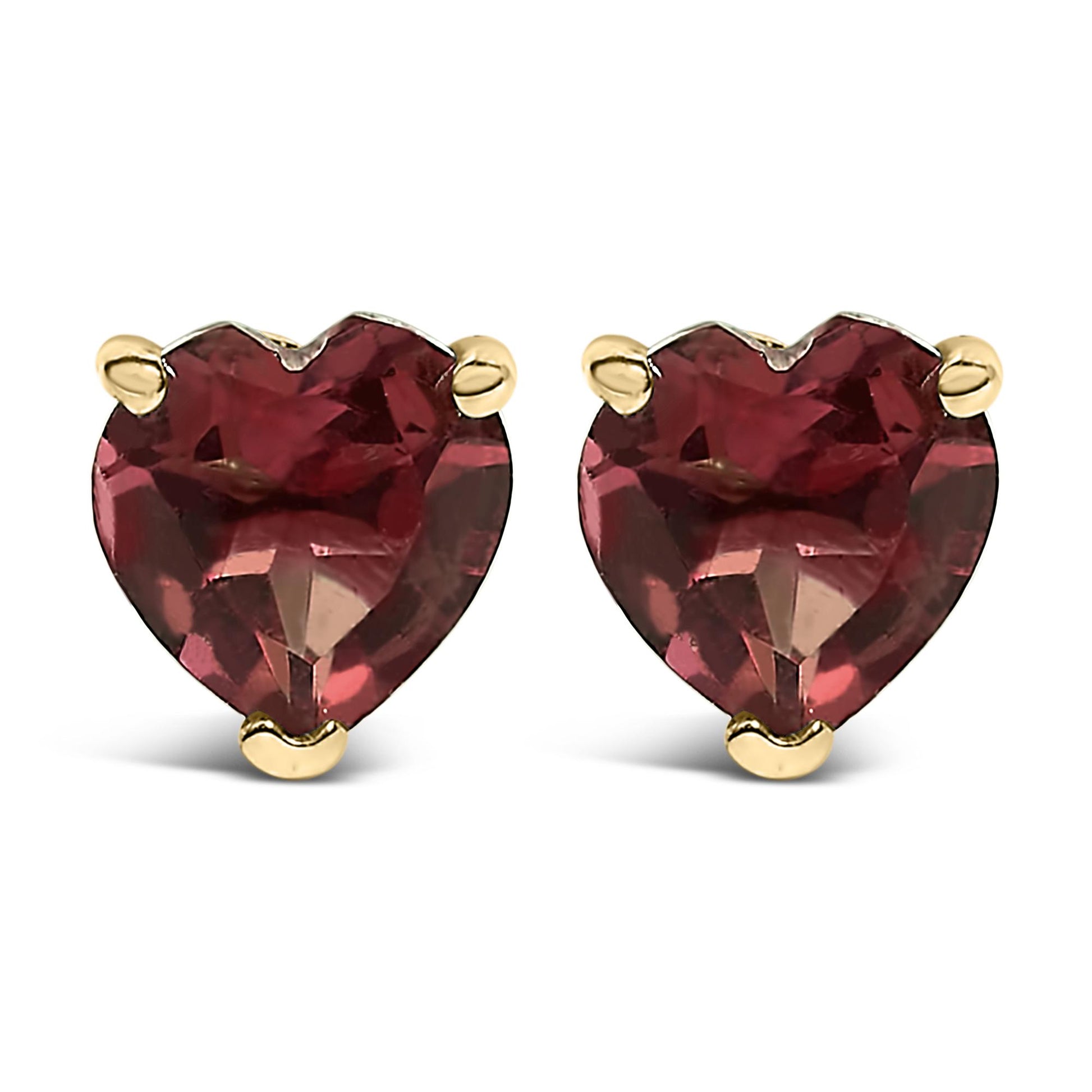 Close-up front view of a pair of yellow metal stud earrings, each featuring a heart-shaped red gemstone set with three prongs.