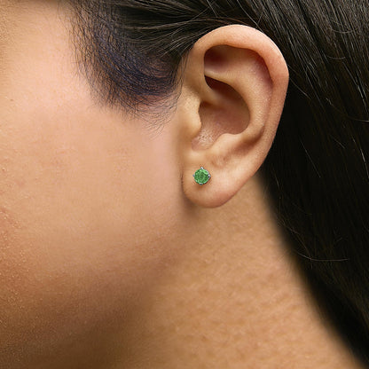 Close-up side view of a model wearing a white metal stud earring with a round green gemstone set in a four-prong setting.