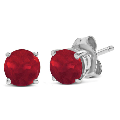 Pair of white metal stud earrings with round red gemstones in a 4-prong setting, shown in a close-up angled view.