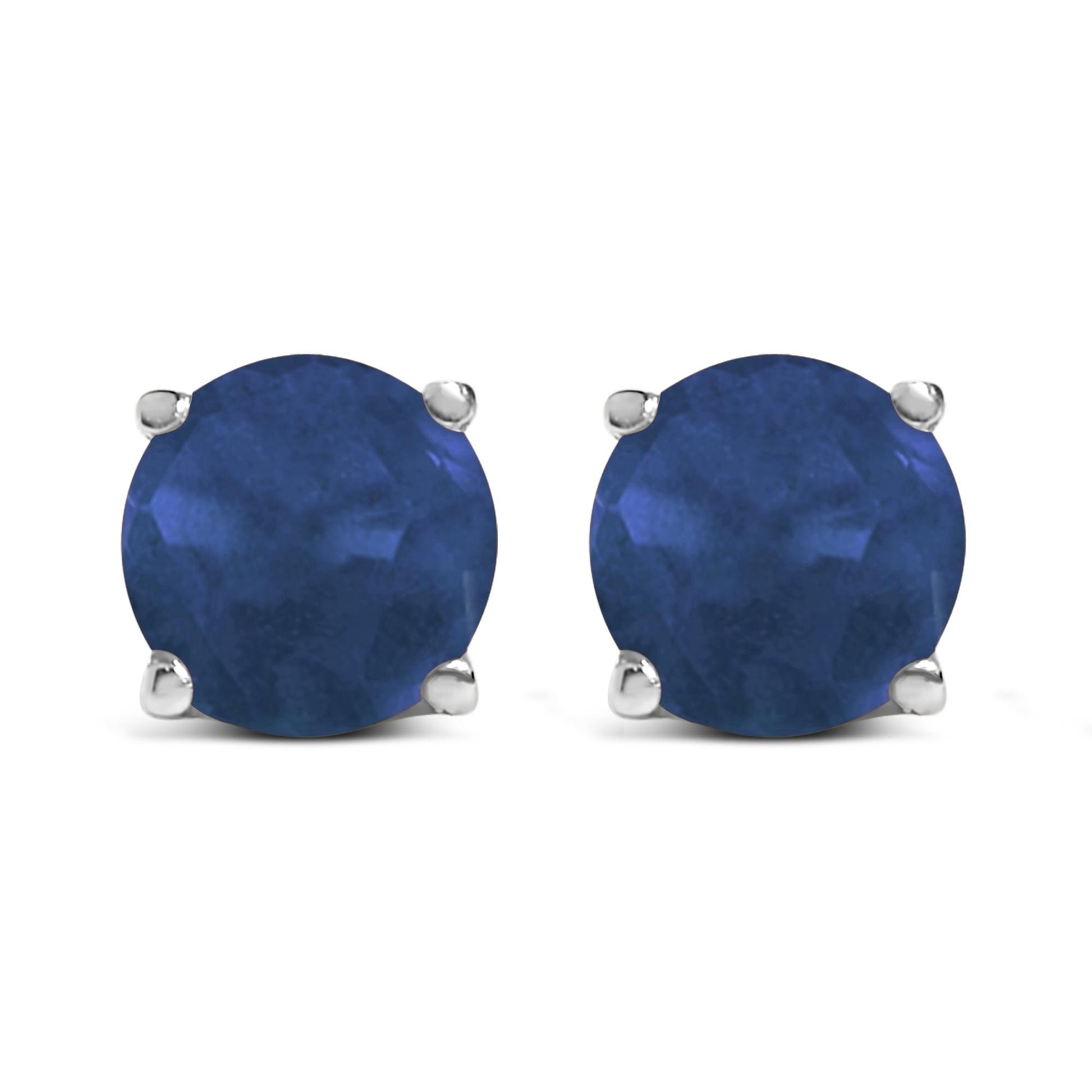 Close-up front view of round blue gemstone stud earrings set in white metal with four-prong settings.