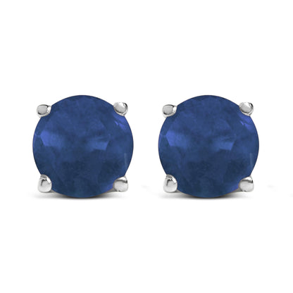 Close-up front view of round blue gemstone stud earrings set in white metal with four-prong settings.