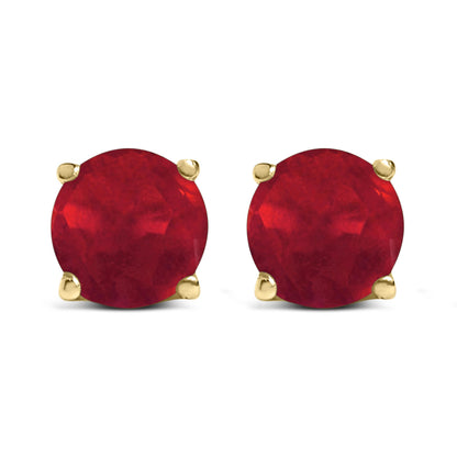 Front view of yellow metal stud earrings featuring round red gemstones in four-prong settings.