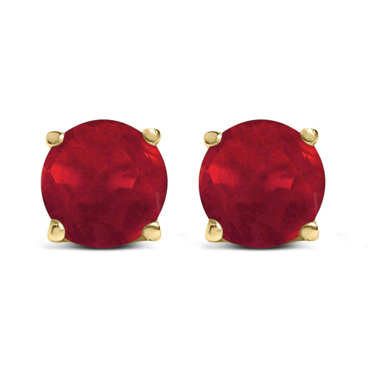 Front view of yellow metal stud earrings featuring round red gemstones in four-prong settings.