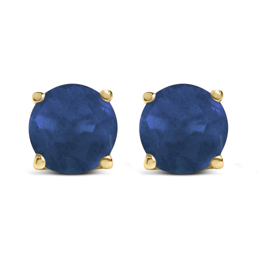 Front view of yellow metal stud earrings with round blue gemstones in four-prong settings.