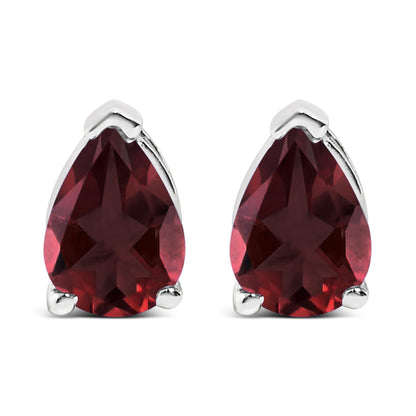 Front view of a pair of white metal earrings featuring pear-shaped red gemstones held by three-prong settings, shown on a white background.