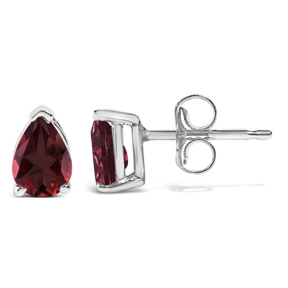 Close-up front and side view of a pair of white metal stud earrings with pear-shaped red gemstones in three-prong settings.