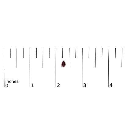White metal pear-shaped red gemstone earring shown on a ruler scale, front-facing angle.