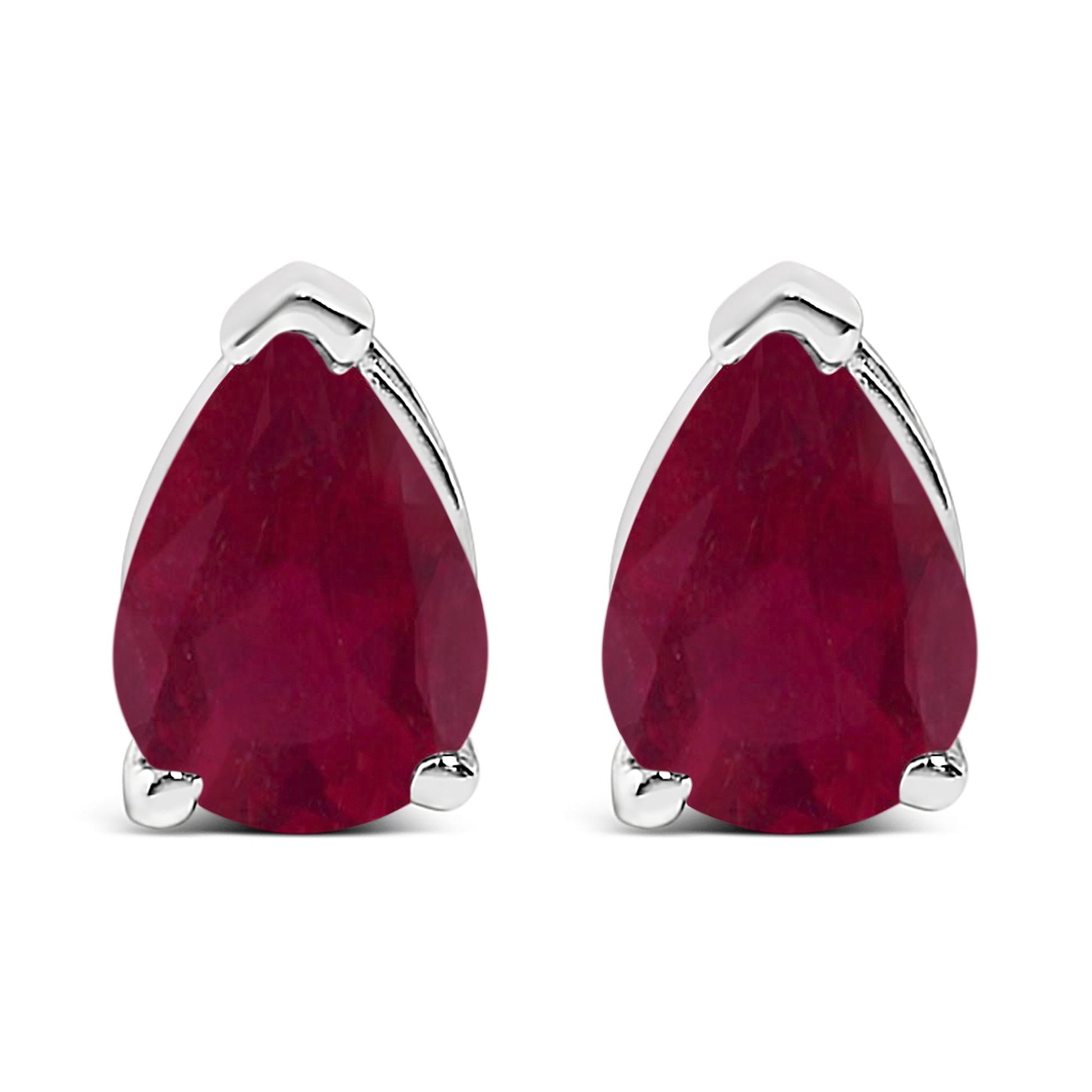 Close-up front view of a pair of white metal earrings, each featuring a pear-shaped red gemstone with a three-prong setting.