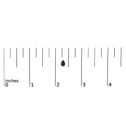 Close-up top view of a pair of white earrings each with a pear-shaped blue gemstone set with three prongs, shown on a ruler scale.