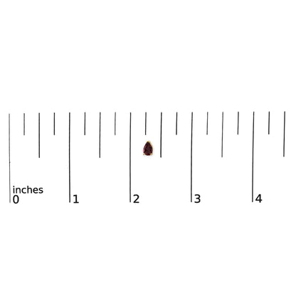 Yellow metal pear-shaped red gemstone stud earring shown on a scale, front view.