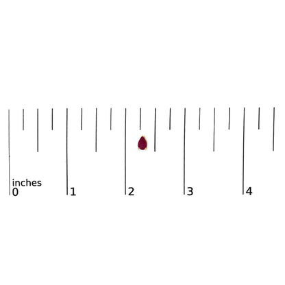 Close-up front view of a single yellow metal earring with a pear-shaped red gemstone set in a three-prong setting, shown on a scale.