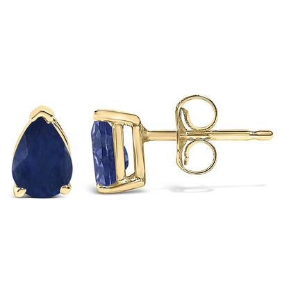Close-up side-by-side view of a pair of yellow metal stud earrings featuring pear-shaped blue gemstones in a three-prong setting.