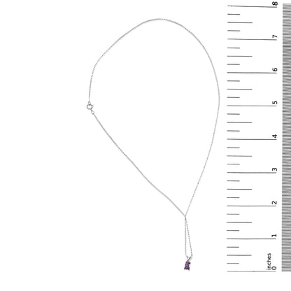 White metal necklace with a white metal chain holding a small emerald-cut purple gemstone pendant in a four-prong setting, shown laid flat next to a ruler for scale.