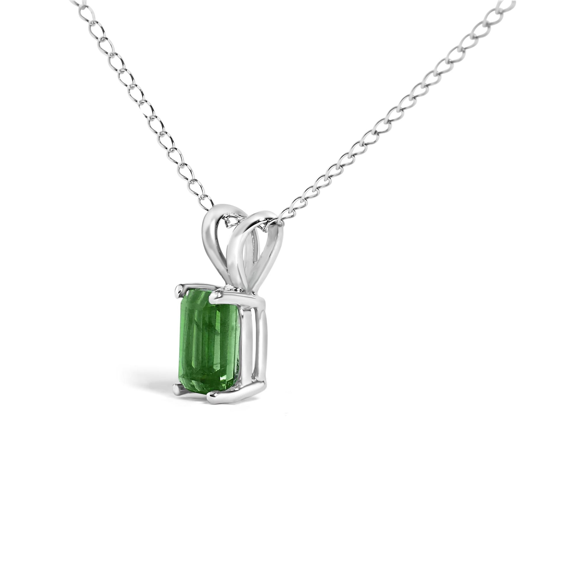 Close-up angled view of a white metal necklace with a rectangular green gemstone pendant set in a four-prong setting.