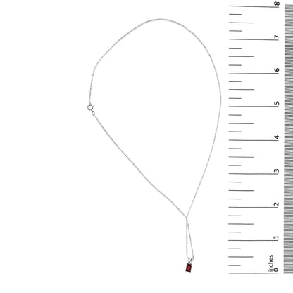 White metal necklace with a single emerald-shaped red gemstone pendant in a 4-prong setting, shown flat on a scale, top-down view.