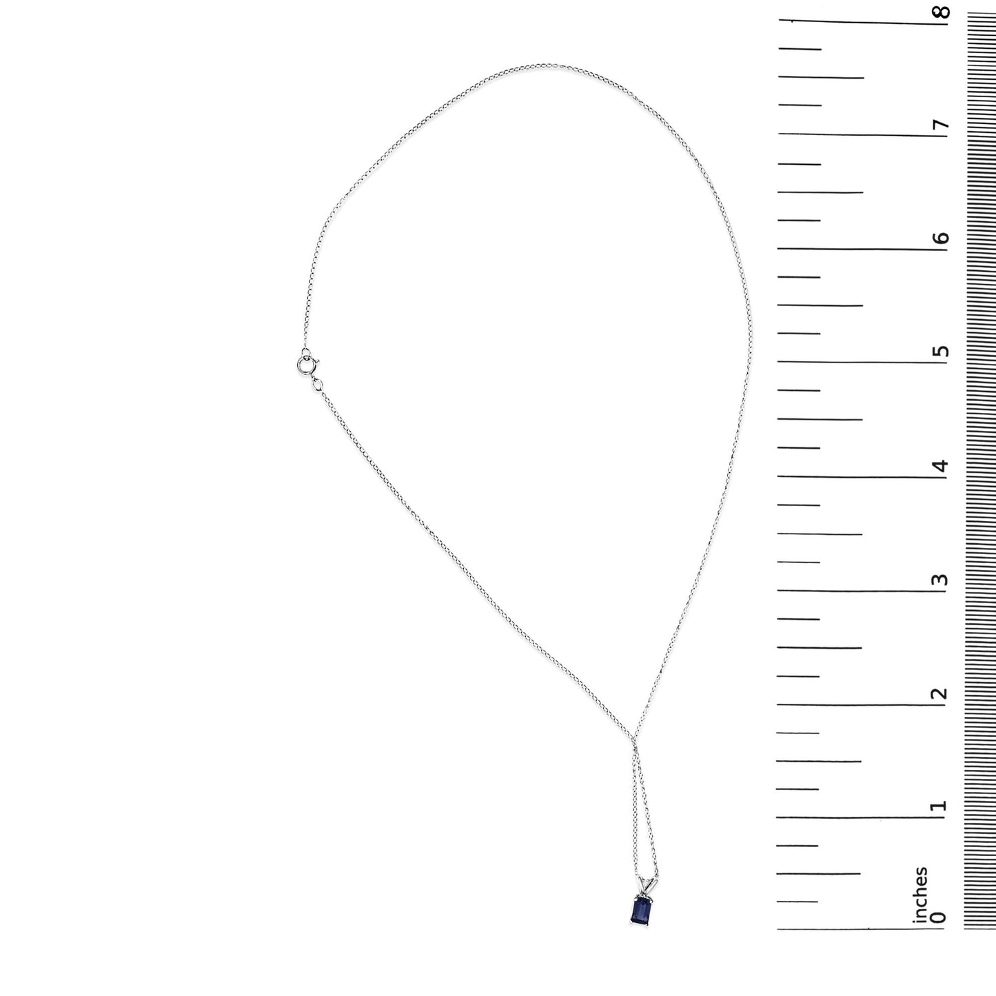 White necklace with a small blue emerald-shaped gemstone pendant set in a 4-prong setting, shown flat on a scale, top-down angle.